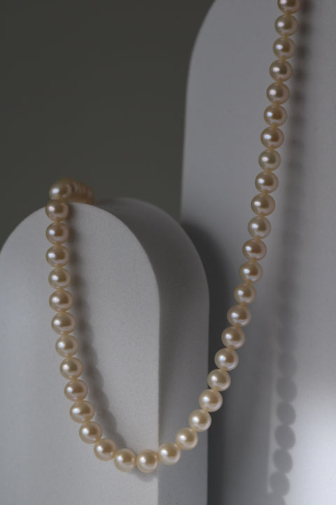 Colier cu perle de cultură champagne Aura, prezentat pe suport decorativ