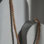 Colier cu perle de cultură roz, prezentat pe suport minimalist