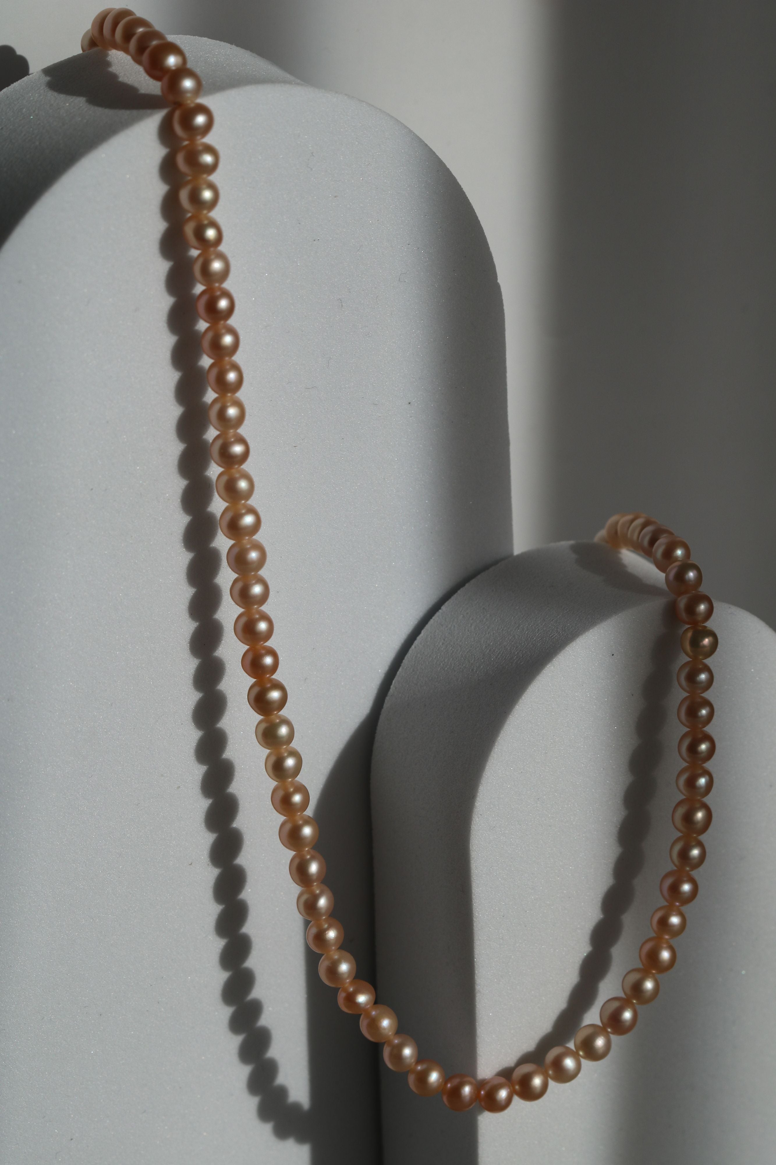 Colier cu perle de cultură roz, prezentat pe suport minimalist