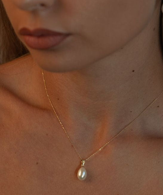 Pandantiv delicat cu perlă naturală albă într-un cadru lifestyle